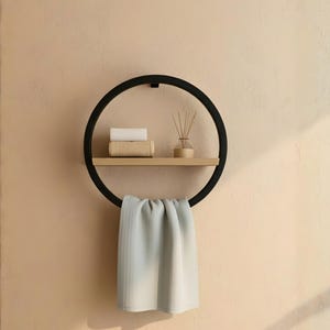 May include: A black circular wall shelf with a wooden shelf and a towel bar. The shelf holds a rolled white towel, a rolled beige towel, and a small wooden diffuser with reeds. A light gray towel hangs from the bottom.