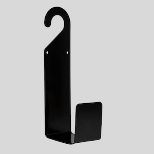 Puede incluir: Un perchero de pared de metal negro con un gancho curvo en la parte superior y una base rectangular. El perchero est&aacute; dise&ntilde;ado para colgar objetos y tiene una est&eacute;tica minimalista y moderna. El perchero es de metal.