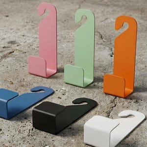 Puede incluir: Colecci&oacute;n de ganchos met&aacute;licos coloridos en rosa, verde y naranja, con forma de gancho en la parte superior y base rectangular. Tambi&eacute;n hay ganchos adicionales en azul, negro y blanco. Estos ganchos est&aacute;n dise&ntilde;ados para colgar objetos.