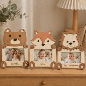 May include: Three wooden photo frames shaped like a bear, fox, and lion. Each frame displays a photograph and has a name. The bear frame says "Family", the fox frame says "Mia", and the lion frame says "My Little Bear".