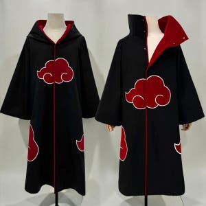 May include: Two black cloaks featuring a red cloud pattern with white outlines. One cloak has a hood and the other has a high collar with visible metal snap buttons. Both garments have a red interior lining and long, wide sleeves.
