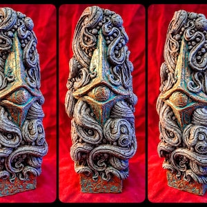 May include: A decorative, hand-painted, ceramic sculpture with a gold and teal color scheme. The sculpture features a stylized eye and intricate, swirling patterns.