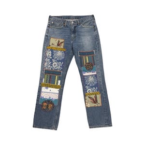 Può includere: Jeans blu con toppe decorative con disegni floreali e a farfalla. Le toppe sono in vari colori, tra cui blu, verde, giallo e arancione. I jeans hanno un classico design a cinque tasche.