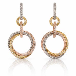 Pode incluir: Um par de brincos pendurados com três argolas interligadas em tons de ouro, ouro rosa e prata, cada uma incrustada com pequenas pedras brilhantes. Os brincos têm um fecho de pino e argola. As joias são exibidas em um fundo branco.