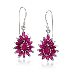 May include: A pair of silver drop earrings featuring a cluster of oval-cut, deep pink gemstones arranged in a floral or starburst pattern. The earrings have a hook closure.