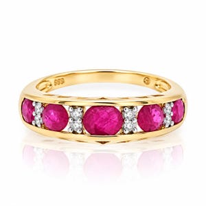 Op de afbeelding: Een gouden ring met een rij van vijf ronde, levendige roze robijnen afgewisseld met kleine, heldere witte diamanten. De binnenkant van de ring is duidelijk gestempeld met het getal 585, wat het goudgehalte van het sieraad aangeeft.