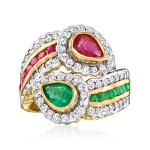 May include: A multi-layered ring featuring a pear-shaped ruby and emerald, surrounded by a halo of small diamonds. The ring has gold and silver accents, with rows of small rubies and emeralds.