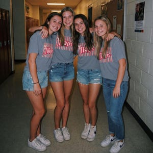 May include: Four individuals wearing grey short-sleeved t-shirts with a red and white striped pennant graphic featuring the text TIGERS. Three individuals wear light blue denim shorts, while one wears light blue denim jeans and white sneakers.