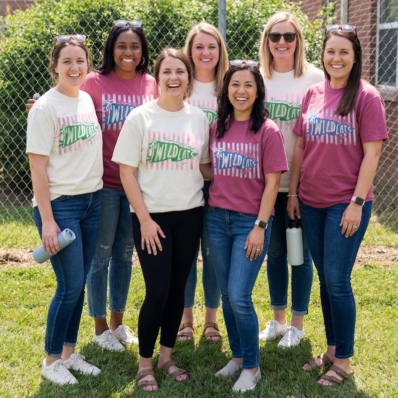 May include: A group of six individuals wearing short-sleeved t-shirts in cream and maroon colors. Each shirt features a graphic with vertical stripes and the text "Waverly High School WILDCATS" in a green or blue banner design, paired with blue jeans.