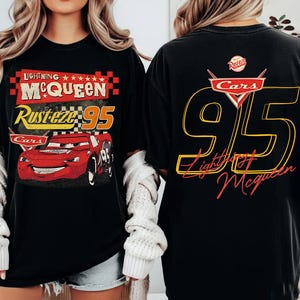 Peut inclure: T-shirt noir avec Lightning McQueen du film Cars. L'avant affiche "Lightning McQueen Rusteze 95" et une voiture de course rouge. Le dos présente un grand "95" et "Lightning McQueen" en jaune et rouge, avec le logo Cars.