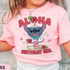May include: Pink t-shirt featuring a graphic of Stitch from Lilo & Stitch on a birthday cake. The text "ALOHA" and "5 BIRTHDAY GIRL" are displayed in red. The shirt is a short-sleeved design.