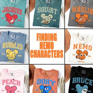 May include: Nine t-shirts featuring characters from the movie "Finding Nemo." Each shirt displays a character's name in a collegiate font, along with an image of the character. The shirts are in various colors, including teal, gray, and peach.