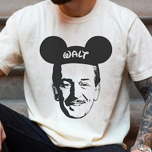 Puede incluir: Camiseta color crema con un gr&aacute;fico en blanco y negro de Walt Disney con orejas de Mickey Mouse y el nombre "WALT" impreso. El dise&ntilde;o est&aacute; centrado en la camiseta.