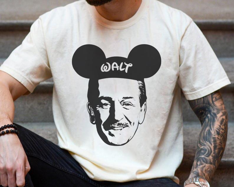Puede incluir: Camiseta color crema con un gr&aacute;fico en blanco y negro de Walt Disney con orejas de Mickey Mouse y el nombre "WALT" impreso. El dise&ntilde;o est&aacute; centrado en la camiseta.