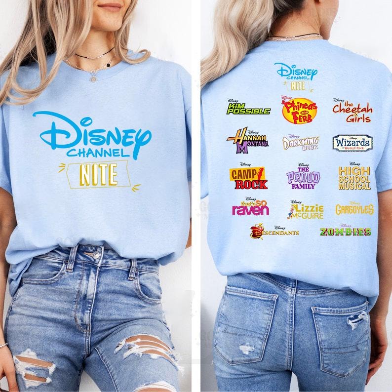 May include: Light blue t-shirt featuring the Disney Channel logo and the word "Nite" in gold. The back of the shirt displays logos from various Disney Channel shows, including "Kim Possible," "Hannah Montana," and "High School Musical."