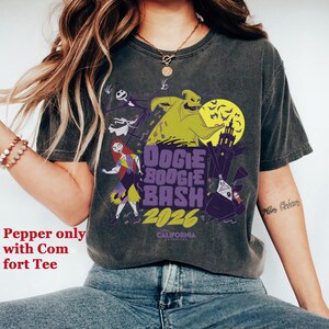 May include: Dark gray t-shirt featuring a graphic design with characters from The Nightmare Before Christmas. The design includes Jack Skellington, Sally, and Oogie Boogie, with the text "Oogie Boogie Bash 2026".