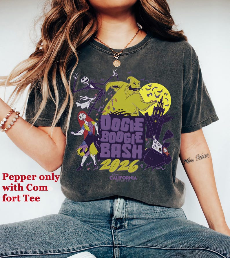 May include: Dark gray t-shirt featuring a graphic design with characters from The Nightmare Before Christmas. The design includes Jack Skellington, Sally, and Oogie Boogie, with the text "Oogie Boogie Bash 2026".