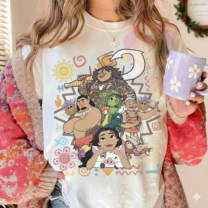 May include: A white t-shirt featuring a colorful graphic of characters from a popular animated movie. The design includes a variety of characters, with a central figure holding a large weapon. The shirt is adorned with decorative elements and is a vibrant piece of apparel.