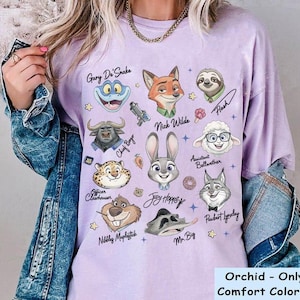 K&ouml;nnte beinhalten: Orchideenfarbenes Comfort Color-Shirt mit Illustrationen von Zeichentrickfiguren aus Zootopia, darunter Judy Hopps, Nick Wilde und Flash. Der Text "Orchid - Only For Comfort Color Shirt" befindet sich unten.