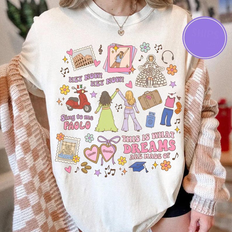 K&ouml;nnte beinhalten: Cremefarbenes T-Shirt mit einem farbenfrohen Grafikdesign mit Illustrationen zum Thema Reisen und Text. Das Design enth&auml;lt Bilder eines Rollers, Sehensw&uuml;rdigkeiten und den Satz "THIS IS WHAT DREAMS ARE MADE OF."