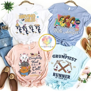 May include: Four t-shirts with graphic prints. The white shirt says "Serving Up Miles" with penguins. The blue shirt says "Miles are better With Amigos" with Disney characters. The pink shirt says "Everybody Want to be a Cat!" with kittens. The light blue shirt says "The Grumpiest Runner of Them All" with pickaxes.
