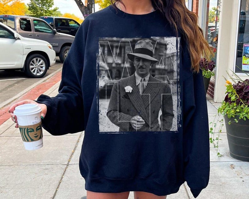 May include: A white ceramic mug with a black handle and the text "But First, Coffee" in a bold, black font. The mug is set against a blurred background, suggesting a cosy setting.