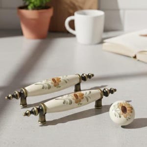 May include: A white ceramic mug with a black handle and the text "But First, Coffee" in a black, bold font. The mug is on a white surface. The mug is approximately 10 cm tall.