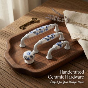 Puede incluir: Juego de herrajes de cerámica hechos a mano con diseños florales blancos y azules. Incluye tres tiradores y un pomo. El texto dice: "Handcrafted Ceramic Hardware Perfect for Your Vintage Home."
