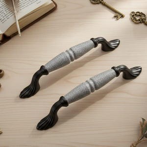 Peut inclure: Un ensemble de trois tasses en céramique avec une finition mate et mouchetée. Les tasses sont de couleur crème, gris clair et gris foncé. Chaque tasse a un design simple et minimaliste et une anse arrondie. Les tasses sont empilées.