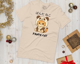 May include: A light beige t-shirt featuring a cartoon illustration of a cat dressed as a panda. The text "PANDA CAT" is below the illustration, with Japanese characters above. The shirt is short-sleeved.