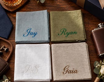 May include: Four square fabric handkerchiefs in light blue, olive green, white, and beige. The blue one is embroidered with Jay, the green with Ryan, the white with P.S, and the beige with Gaia in cursive script lettering.
