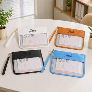 May include: Four clear pouches with colored tops and wrist straps. The pouches are white, brown, black, and blue. Each pouch has the name "Jack" printed on the top. The pouches are filled with papers and have gold-colored zippers.