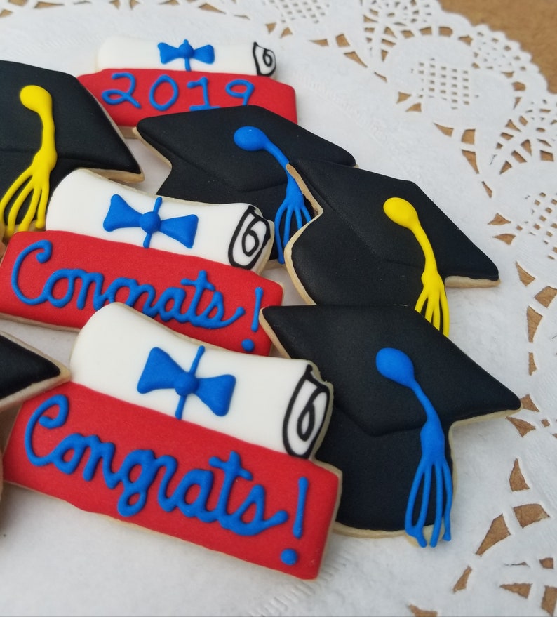 May include: A set of graduation cookies decorated with black graduation caps, red, white, and blue diplomas, and the words "Congrats!" and "2019".