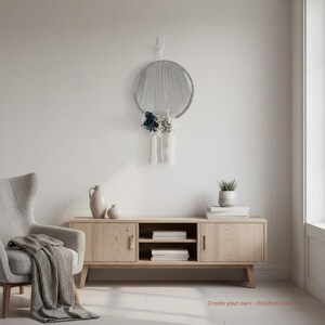 May include: A circular wall hanging featuring a grey cord frame with radiating grey strings and a cluster of dark blue, grey, and white fabric tassels at the bottom. The text "Create your own - finished look" is visible in the lower right corner.