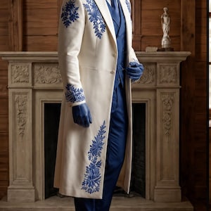 Puede incluir: Un abrigo largo de color crema con intrincados bordados florales azules en los hombros, pu&ntilde;os y dobladillo. El abrigo se lleva sobre un chaleco azul, una corbata azul y pantalones azules. El conjunto incluye guantes de cuero azul y zapatos de vestir negros.