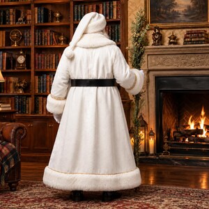 May include: A floor-length white faux fur coat with a matching hat, featuring a wide black belt at the waist and gold trim along the cuffs and hem. The garment has a thick collar and long sleeves, providing a full-coverage, textured appearance.