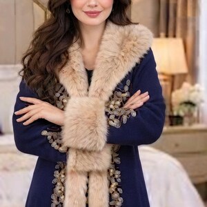 May include: A navy blue coat featuring a thick beige faux fur collar and cuffs. The garment is adorned with intricate gold and silver floral embroidery along the front panels, extending from the neckline down to the hem in a detailed botanical pattern.