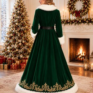 K&ouml;nnte beinhalten: Ein bodenlanges dunkelgr&uuml;nes Samtkleid mit wei&szlig;em Kunstfellkragen und &Auml;rmelb&uuml;ndchen, einem schwarzen Tailleng&uuml;rtel sowie einem goldenen Stickmuster am Saum, der mit einem breiten wei&szlig;en Kunstfellbesatz versehen ist.