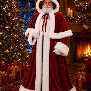 May include: A floor-length, deep red velvet cloak featuring a thick white faux fur trim along the hood, front opening, and cuffs. The garment includes a matching red ribbon tie closure at the neck and is worn with white gloves.