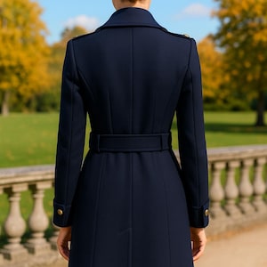 May include: A navy blue long coat featuring a structured collar, shoulder epaulets with gold buttons, and a matching waist belt. The coat has long sleeves with gold button cuffs and a tailored back design with vertical seams and a central vent.