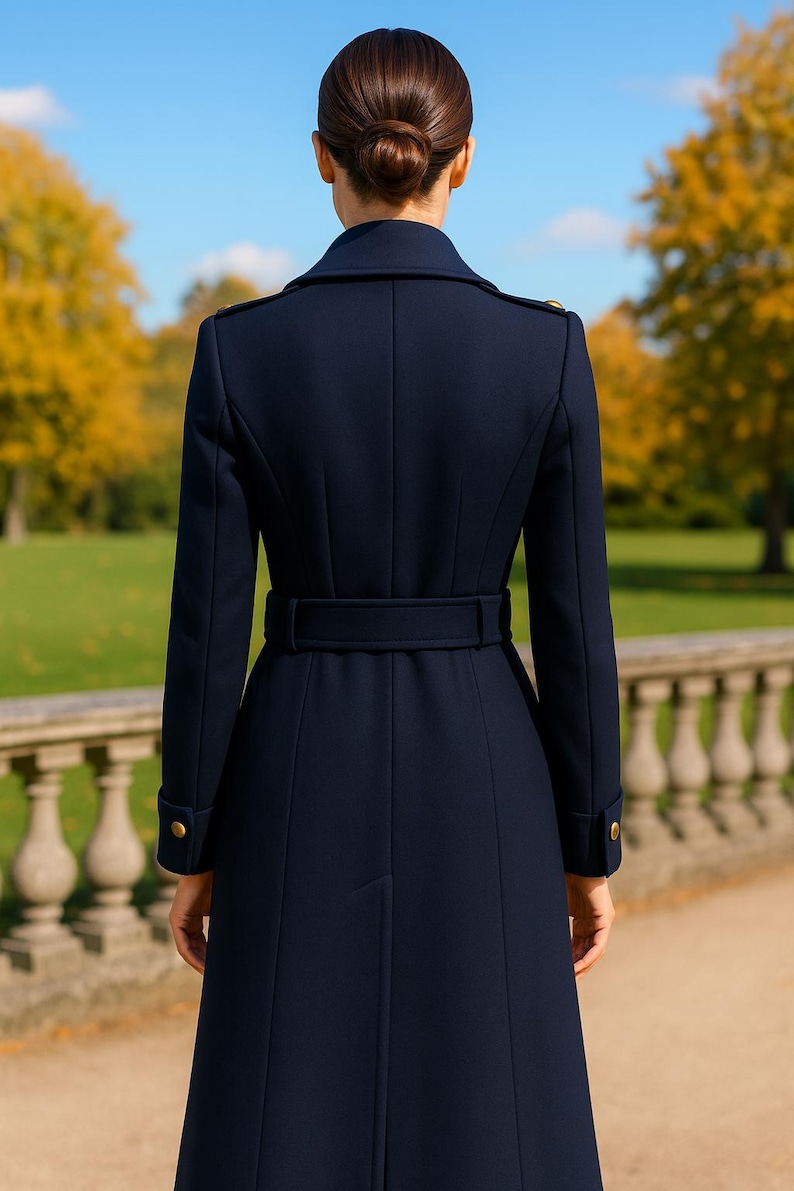 May include: A navy blue long coat featuring a structured collar, shoulder epaulets with gold buttons, and a matching waist belt. The coat has long sleeves with gold button cuffs and a tailored back design with vertical seams and a central vent.