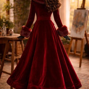 May include: A floor-length, deep red velvet coat featuring a wide, plush faux fur collar and matching faux fur cuffs on the long sleeves. The coat has a fitted bodice with a defined waistline and a full, flared skirt that reaches the floor.