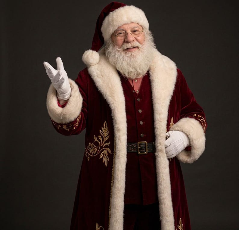 May include: A person dressed as Santa Claus wearing a deep red velvet coat with gold embroidery, a white faux fur trim, and a matching hat. The outfit includes a dark vest, a black belt with a gold buckle, and white gloves.