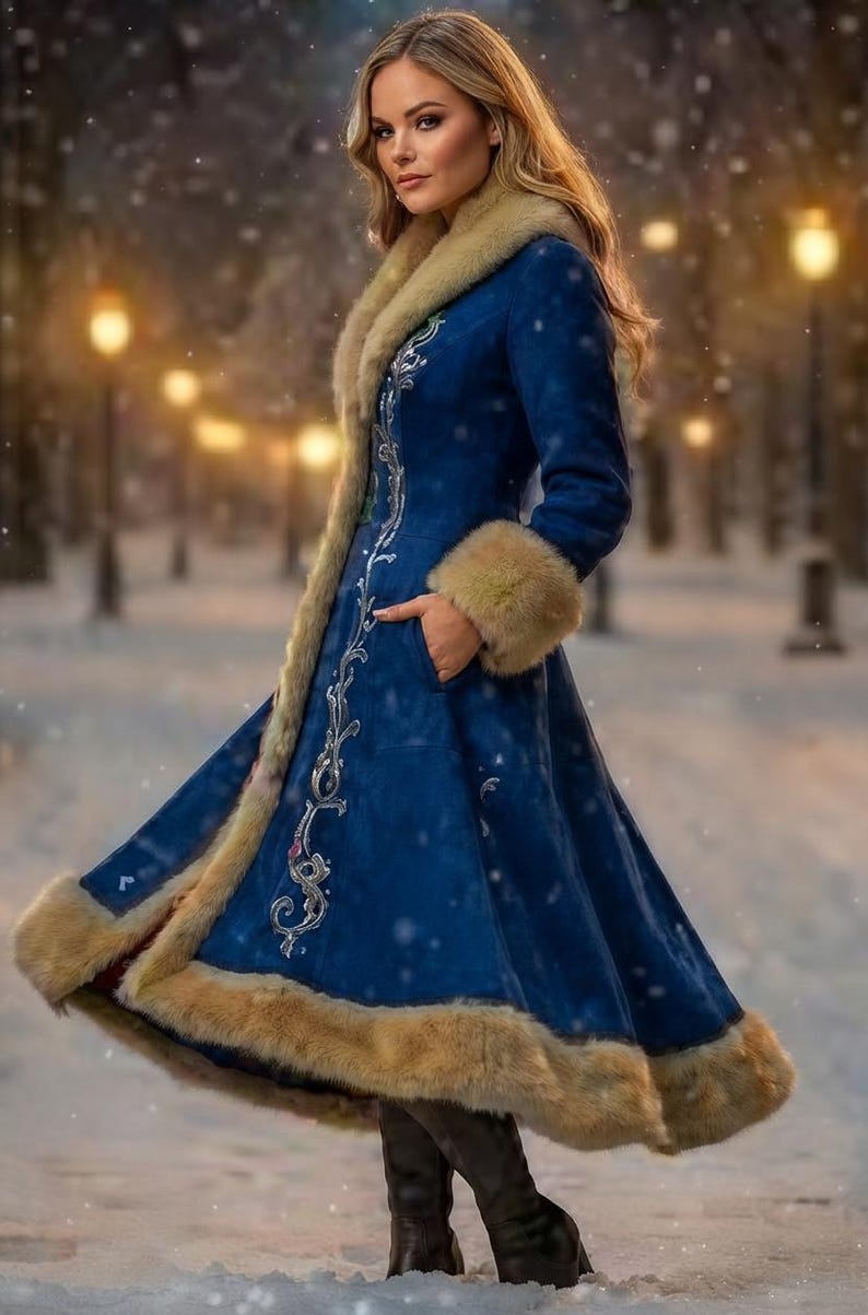 May include: A long, deep blue coat featuring a tan fur-trimmed collar, cuffs, and hem. The coat displays intricate silver embroidery along the front opening and is worn with dark boots in a snowy outdoor setting with blurred lights.