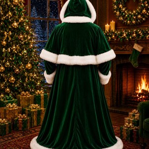 May include: A floor-length dark green velvet cloak featuring a hood, long sleeves, and a capelet overlay. The garment is trimmed with thick white faux fur along the hood edge, the capelet hem, the sleeve cuffs, and the bottom hem.