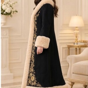 Pu&ograve; includere: Un cappotto lungo nero con un bordo spesso in pelliccia sintetica beige lungo il colletto, i polsini e l'orlo. Il pannello frontale &egrave; decorato con intricati ricami floreali dorati che corrono verticalmente lungo il capo.