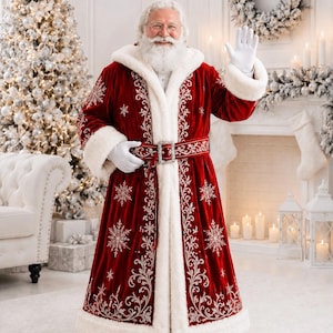 May include: A floor-length red velvet coat with a white faux fur hood, cuffs, and hem. The coat features intricate silver embroidery in floral and snowflake patterns, a matching belt with a silver buckle, and white gloves.