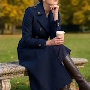 May include: A navy blue double-breasted wool coat featuring silver-toned buttons on the front, shoulders, and cuffs, paired with dark brown leather knee-high boots. The coat has a structured collar, long sleeves, and a tailored fit that reaches below the knee.