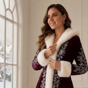 May include: A deep burgundy velvet coat featuring a white faux fur hood and cuffs. The coat is adorned with intricate silver embroidery and sequin detailing along the front opening and sleeves, creating a decorative pattern against the dark fabric.
