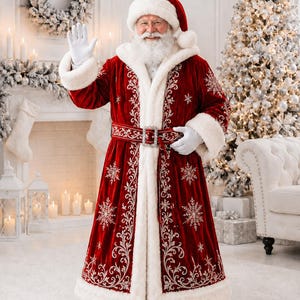 May include: A long red velvet coat with white faux fur trim, featuring silver snowflake embroidery and scrolling patterns. The coat includes a matching red hat with a white pom-pom, a wide belt with a silver buckle, and white gloves.